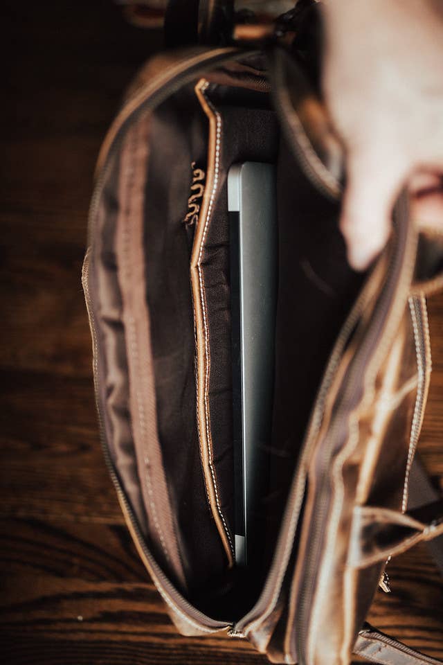 Closeup photo of the interior compartment of a leather pilot bag with laptop inside.