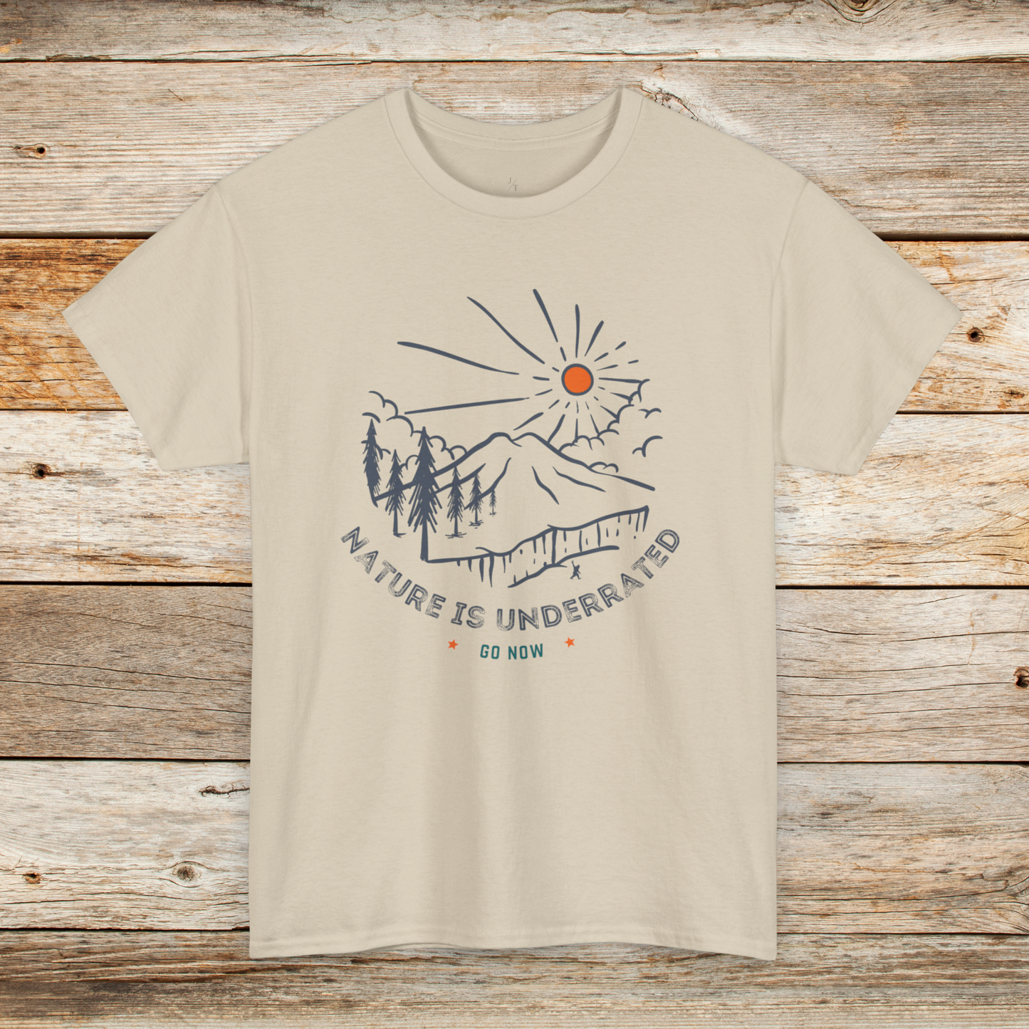 A Sand colored tee shirt with Nature is Underrated graphic with mountains, trees and sunshine.