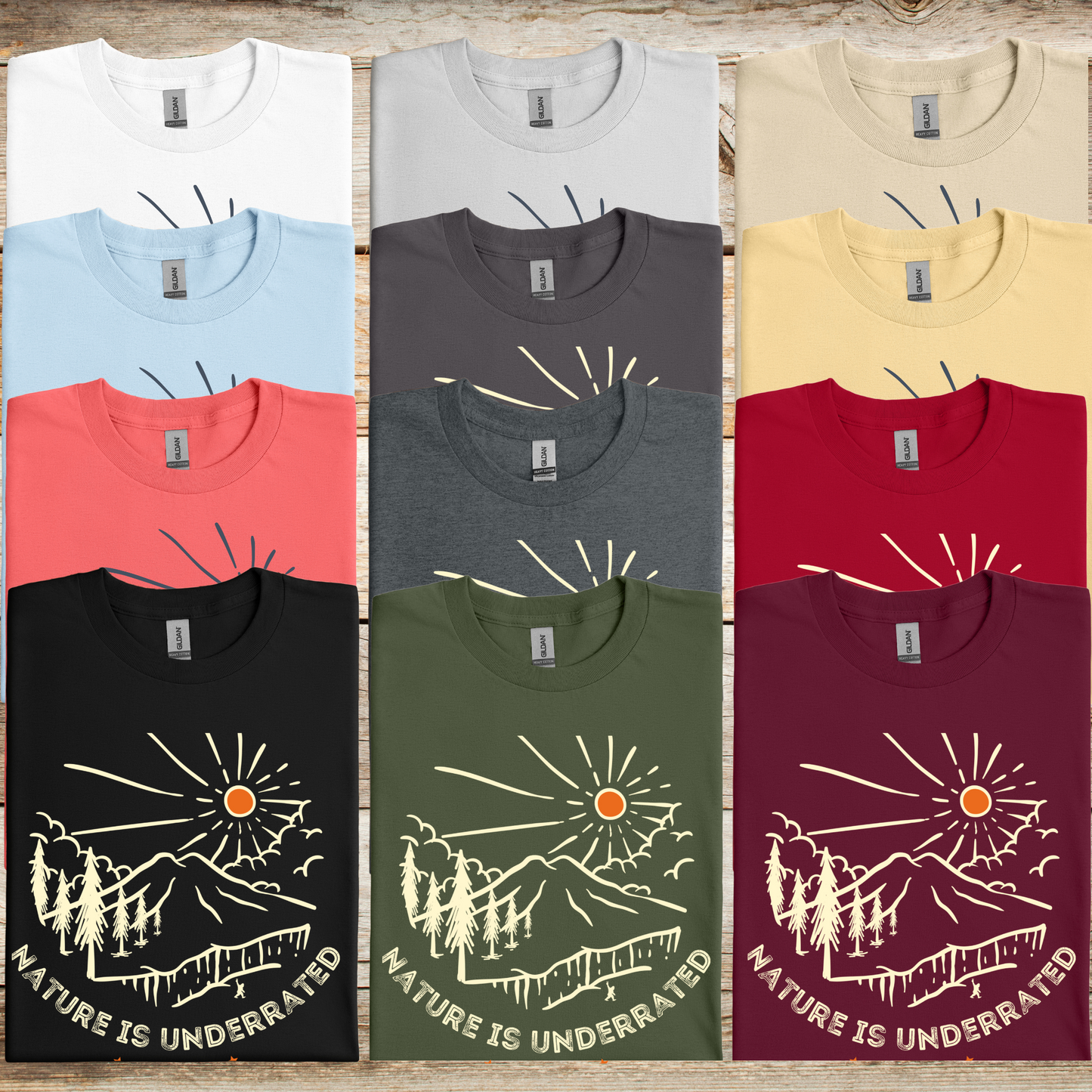 A stack of Nature Is Underrated Tee shirts showing the available color options: white, ice gray, sand, light blue, charcoal, yellow haze, coral silk, dark heather, cardinal red, black, military green, and maroon.