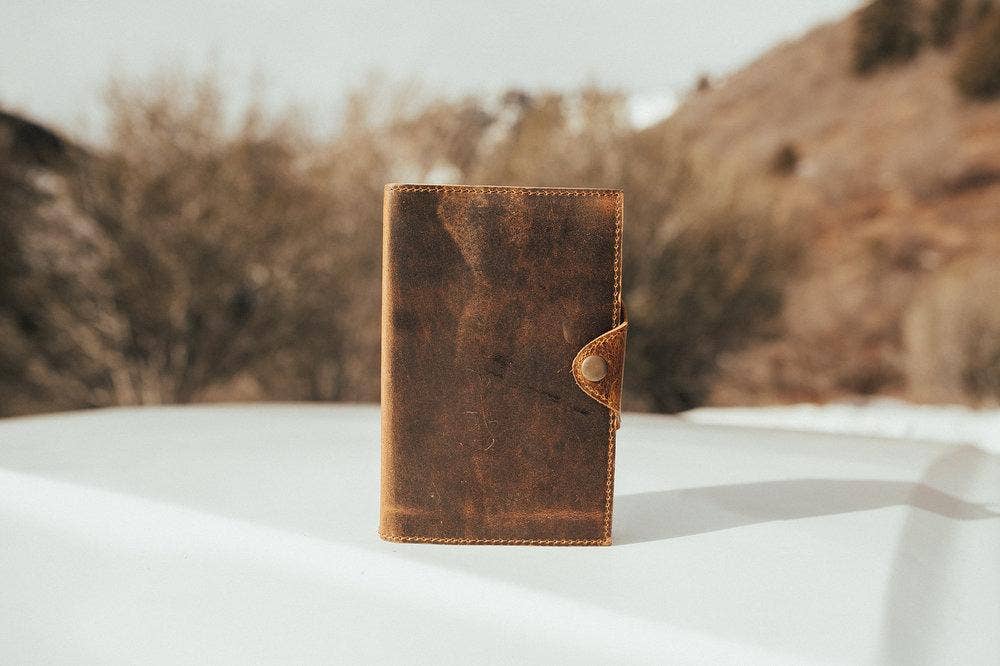 Snap closure leather journal on a table outside.