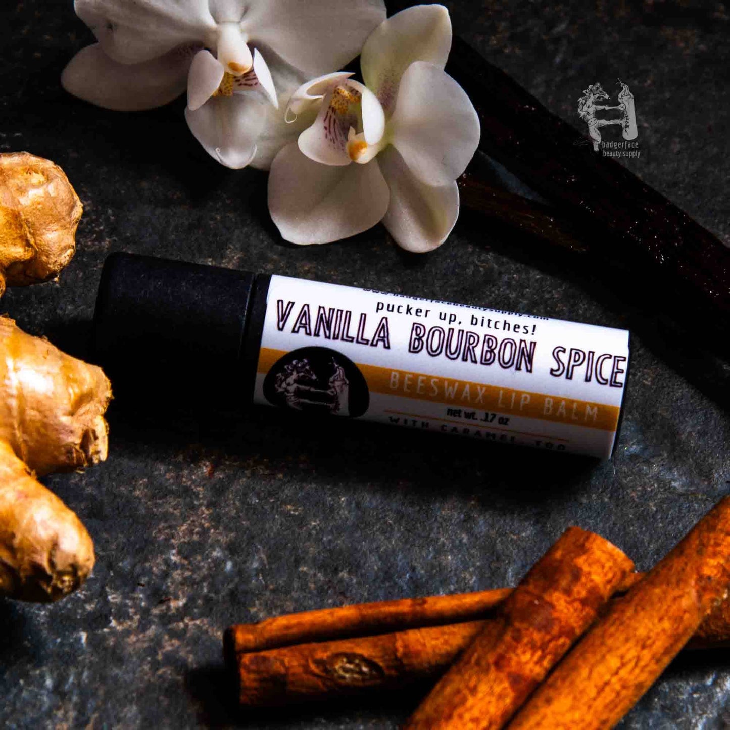 An earthy photo showing cinnamon sticks, a piece of ginger and vanilla flowers with a tube of Vanilla Bourbon Spice lip balm. The label text shows, "Pucker up, bitches!"