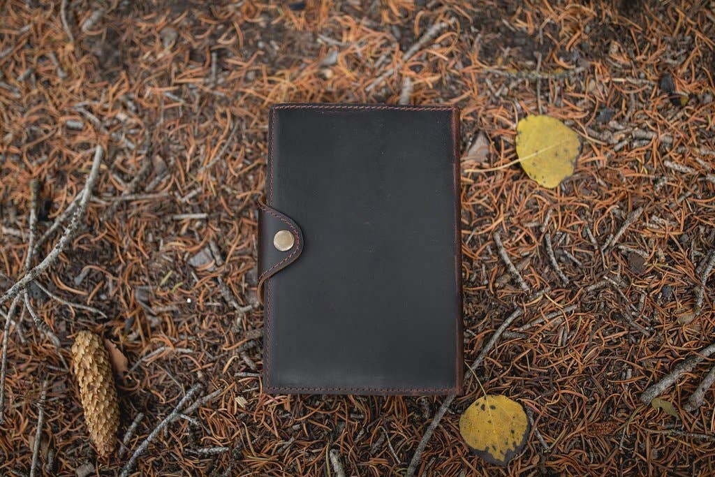 Snap closure leather journal sitting on the ground.