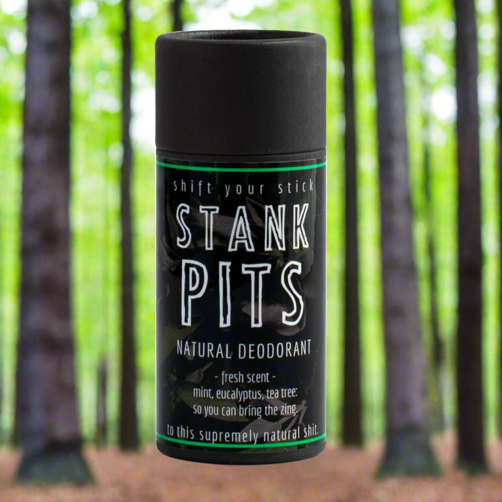 A stick of Stank Pits Natural Deodorant in Fresh Scent shown in an outdoor woodsy environment.