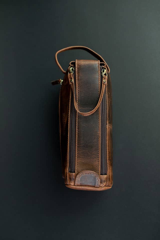 Brown leather toiletry bag on a dark gray background