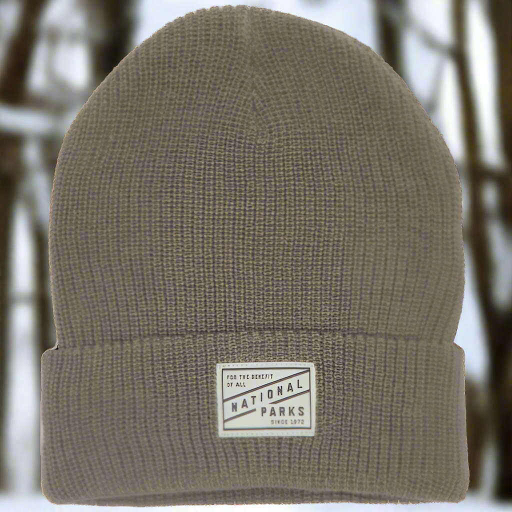 The 1872 National Parks beanie in brown with winter trees blurred in the background.