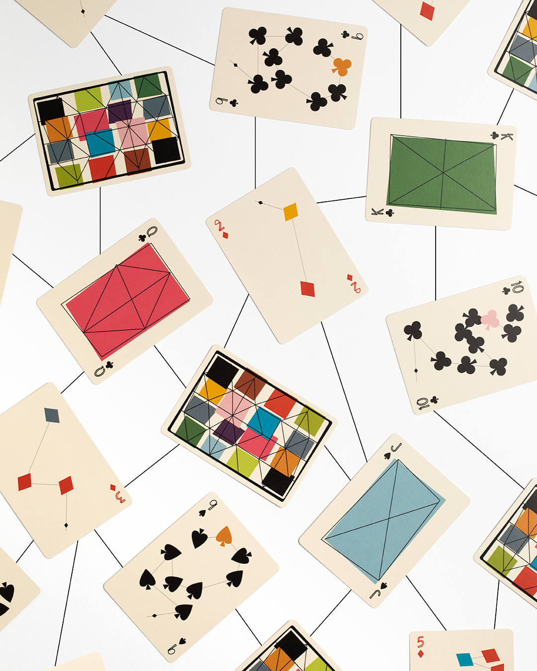 Several uniquely designed playing cards are scattered face up on a white table. There are black lines drawn to connect one card to the next.